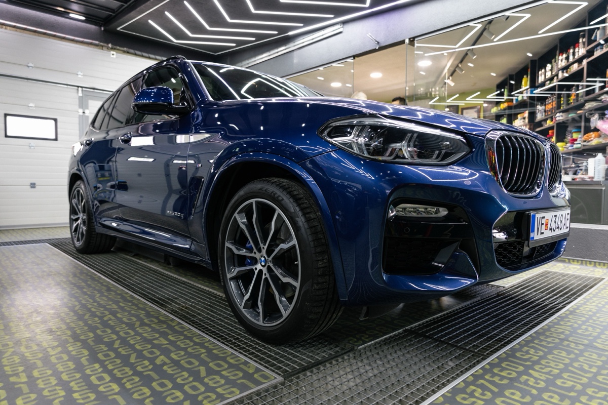 SUV BMW azul recém-polido e brilhando dentro de um estúdio de estética automotiva com iluminação de LED