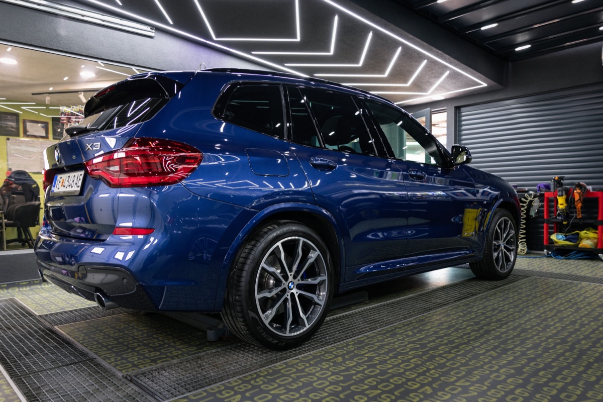 SUV BMW azul recém-polido dentro de um box de estética automotiva com iluminação de LED