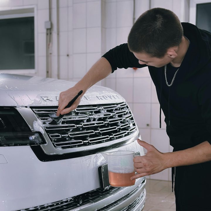 Profissional de estética automotiva limpando a grade de um carro